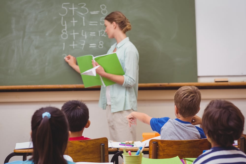 teacher in Manhattan writing on a chalk board in front of her class on 9/11